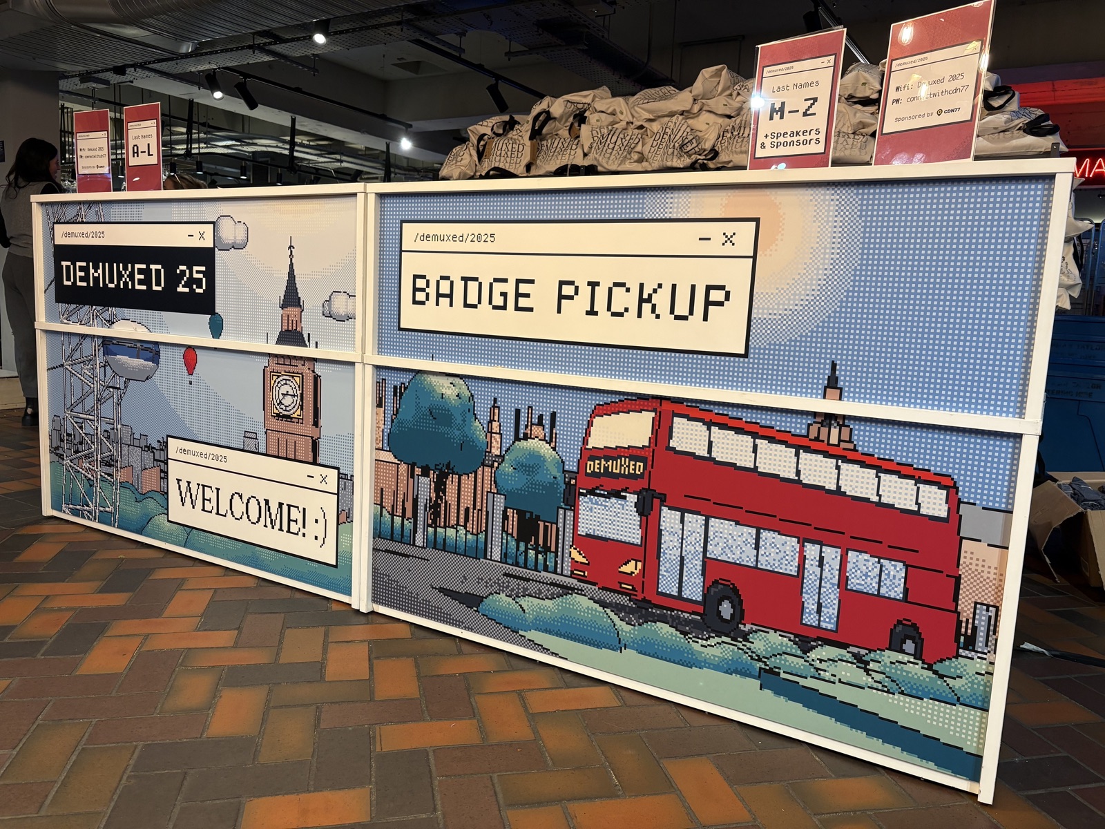 Demuxed 2025 badge pickup signage with London illustrations
